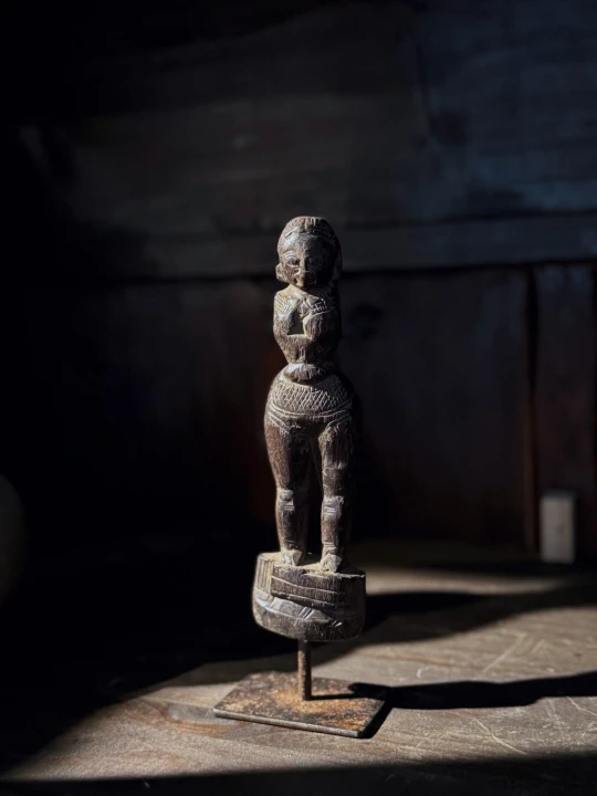 Drewniana kobieca figura rytualna z Indonezji wyeksponowana w aranżacji wnętrza