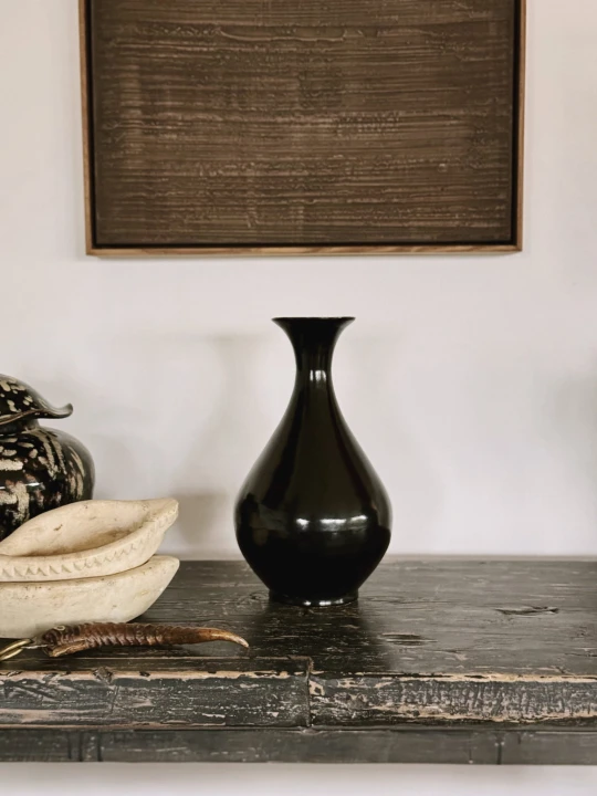Stylowa aranżacja wnętrza prezentująca czarny chiński wazon ceramiczny Jian ware z błyszczącym szkliwem na tle dekoracji